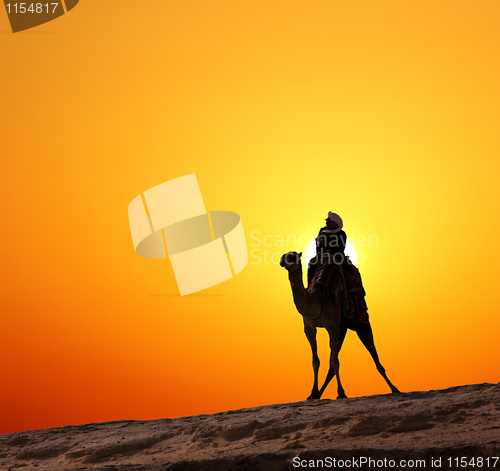 Image of bedouin on camel silhouette against sunrise