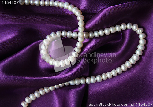 Image of White pearls on a lilac silk as background 