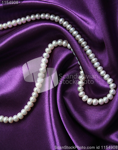 Image of White pearls on a lilac silk as background 