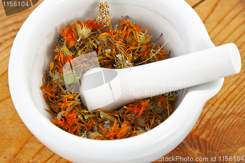 Image of white mortar with dry marigold flower