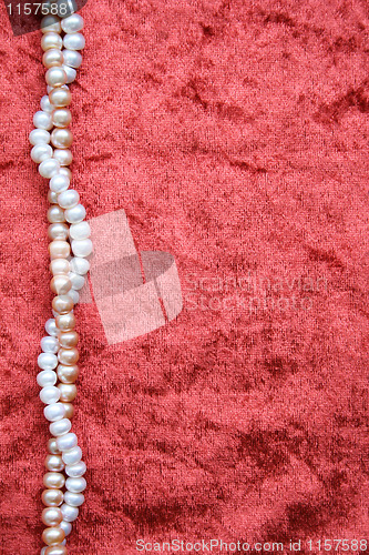 Image of White and pink pearls on the terracotta velvet background