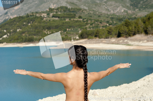 Image of Woman enjoying early morning yoga on the shores of a lake