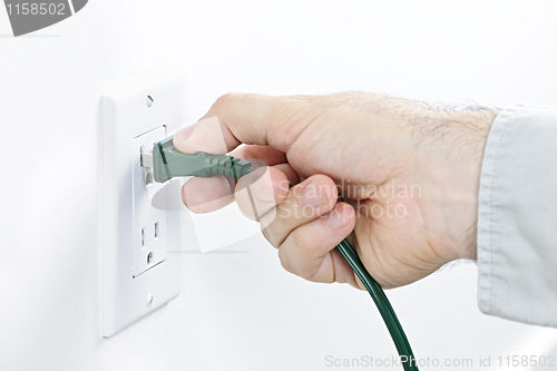 Image of Hand inserting plug into outlet