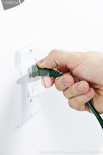 Image of Hand inserting plug into outlet