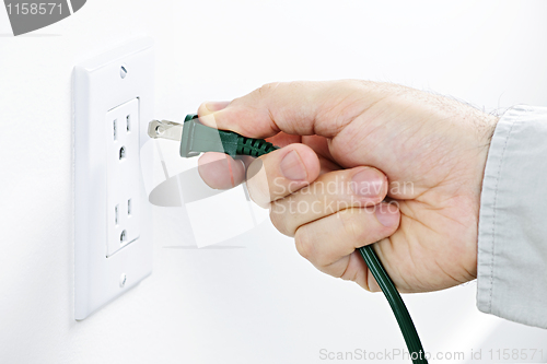 Image of Hand inserting plug into outlet