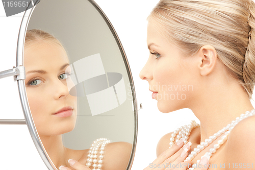 Image of beautiful woman with pearl beads and mirror