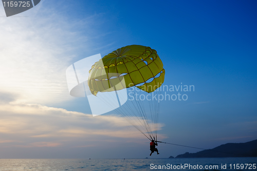 Image of Man parasailing at sunset