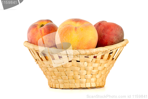 Image of Three tasty peaches in wicker basket