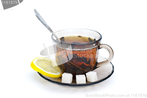 Image of Teacup with black tea, teaspoon, dish, lemon slice and some sugar pieces
