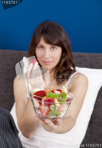 Image of Girl on bed eating fruits