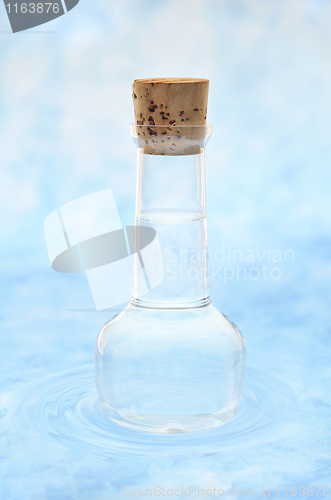 Image of Bottle of clean  water  in water ripples over colored background