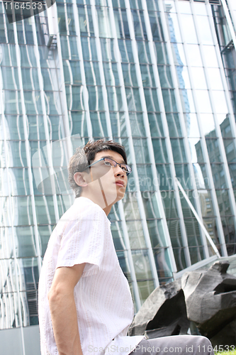 Image of businessman sitting on a bench in front of an office building 