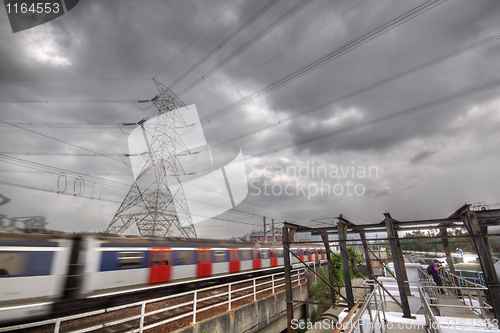 Image of passenger trains in motion and power tower on background