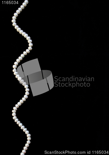 Image of White pearls on the black silk as background 