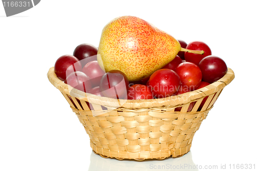 Image of Wicker basket with cherry plums and yellow-red pear