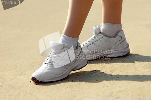 Image of Female legs in sneakers on sand