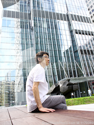 Image of businessman sitting on a bench in front of an office building 