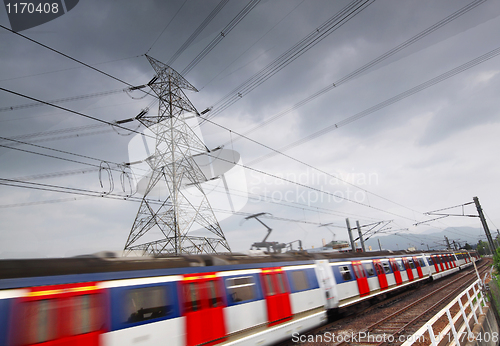 Image of passenger trains in motion and power tower on background