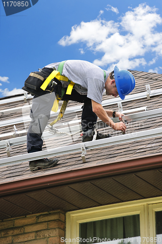 Image of Man working on roof installing rails for solar panels