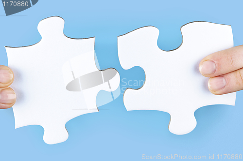 Image of Fingers holding jigsaw puzzle pieces