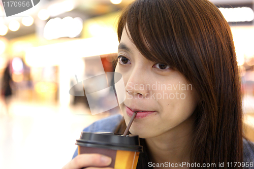 Image of woman sitting in cafe indoor and drinking coffee
