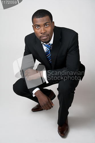 Image of Business man in black suit squatting