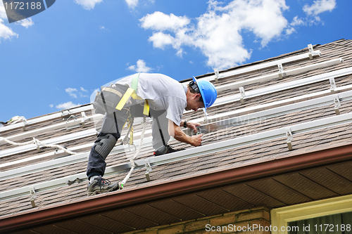 Image of Man working on roof installing rails for solar panels