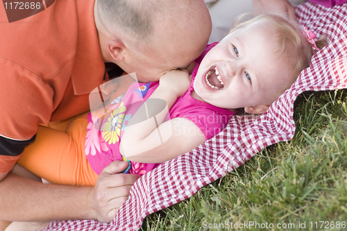 Image of Loving Dad Tickles Daughter in Park