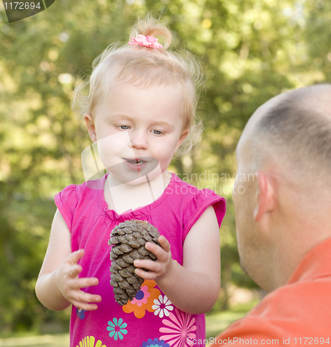 Image of Young Girl Holding Pinecone with Her Dad in Park