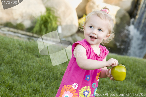 Image of Smiling Young Girl in The Park Holding Apple