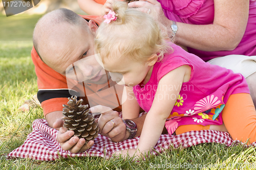 Image of Father and Daughter Talk about Pine Cone in Park