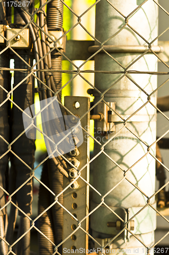 Image of power lines and pipes with steel fence