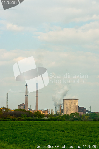 Image of power plant with green grass and smoke rising