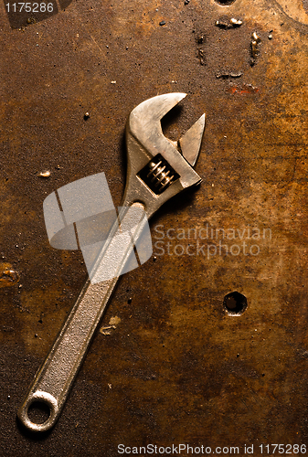 Image of Adjustable wrench on rusty metal plate