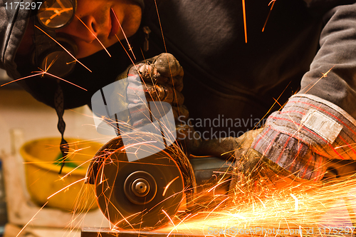 Image of Worker cutting metal with many sharp sparks
