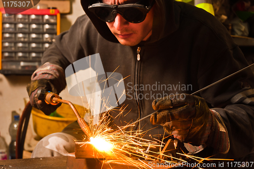 Image of worker welding with hot flame and sparks