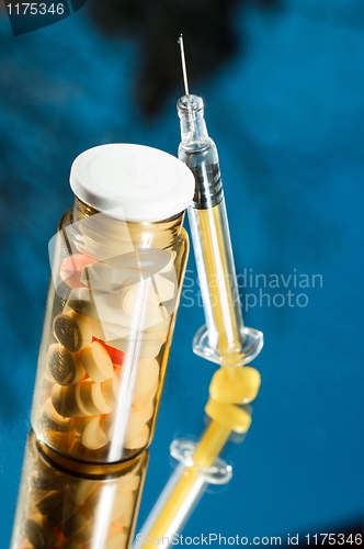 Image of Medicine bottle with sirynge on blue background with reflection