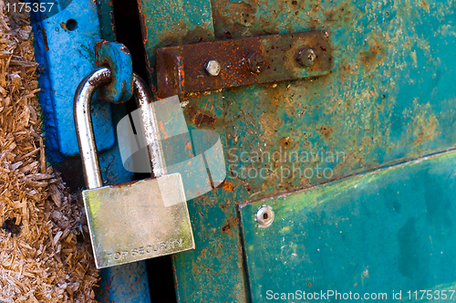 Image of Rusty old padlock on metal door