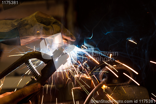 Image of worker welding steel with white sparks