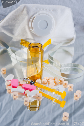 Image of Medicine spilled out of bottle with syringe and protective mask