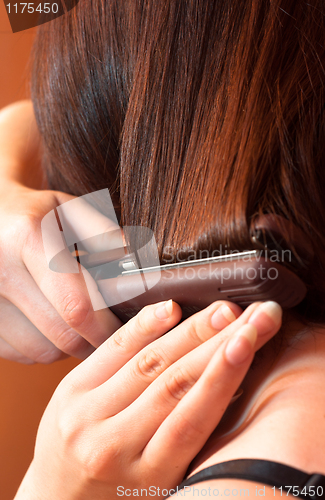 Image of Girl using iron on her hair