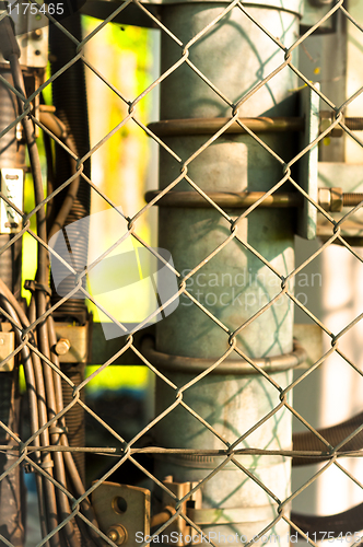 Image of power lines and pipes with steel fence