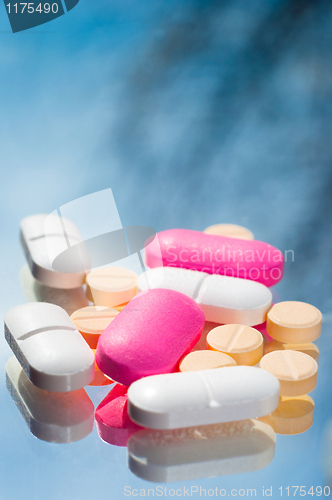 Image of White purple and yellow pills with reflection on blue background