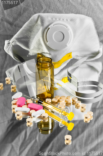 Image of A protective mask and a medicine bottle with pills and syringe