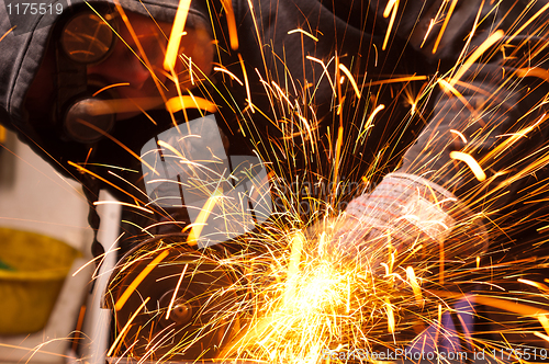 Image of Worker cutting metal with many sharp sparks