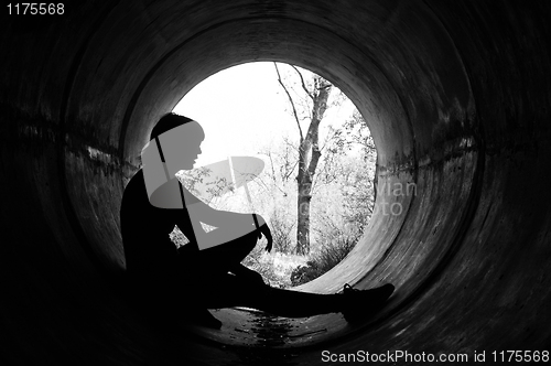 Image of Silhouette of a young girl in sewer pipe