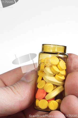 Image of Hand holding medicine bottle full of pills