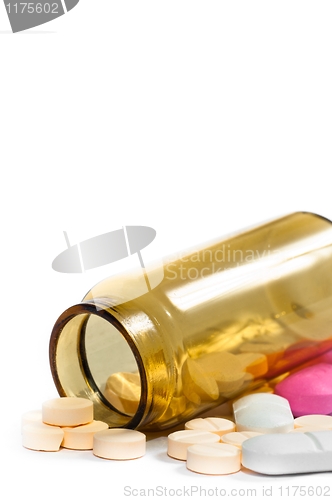 Image of Medicine bottle with purple and yellow pills against white isola