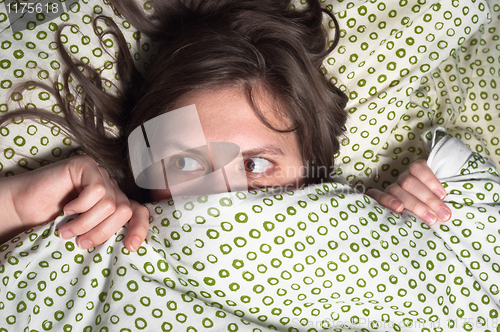 Image of Girl in bed at home hiding under the blanket