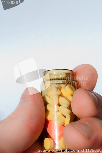 Image of Hand holding medicine bottle full of pills